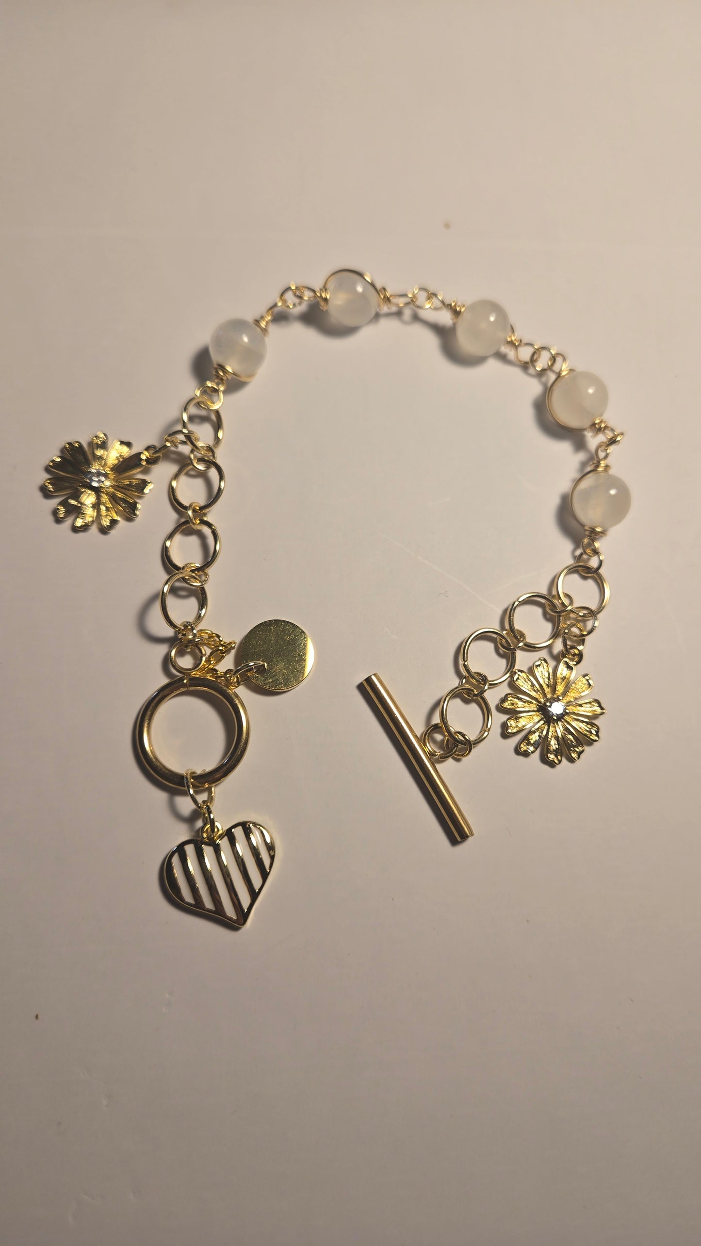 Close-up of Charming Touch bracelet featuring white pearls and golden charms