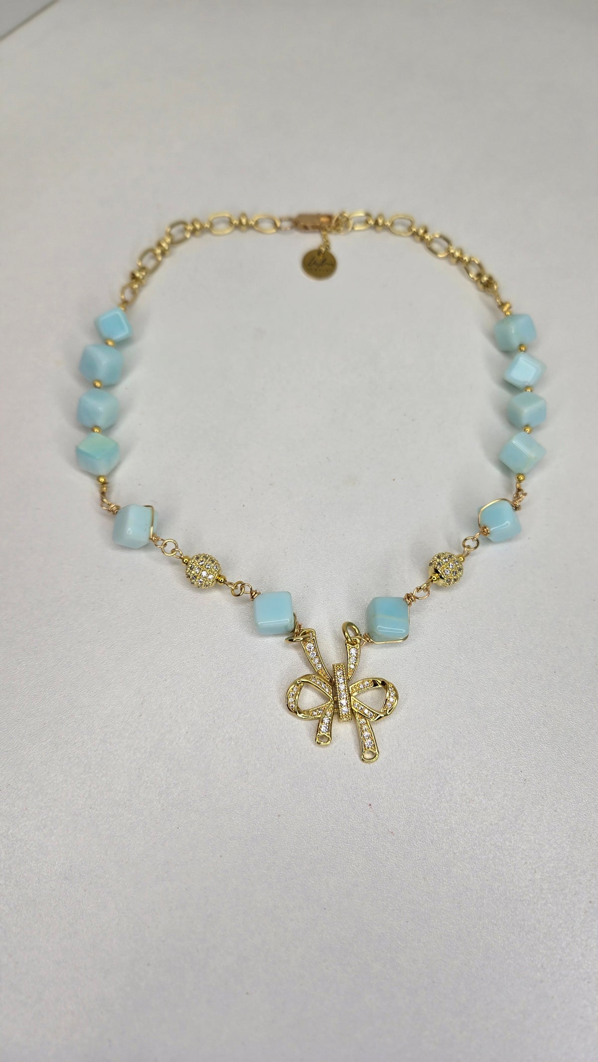 Blue Sky Ribbon Necklace with blue stone beads, zircon accents and a ribbon pendant