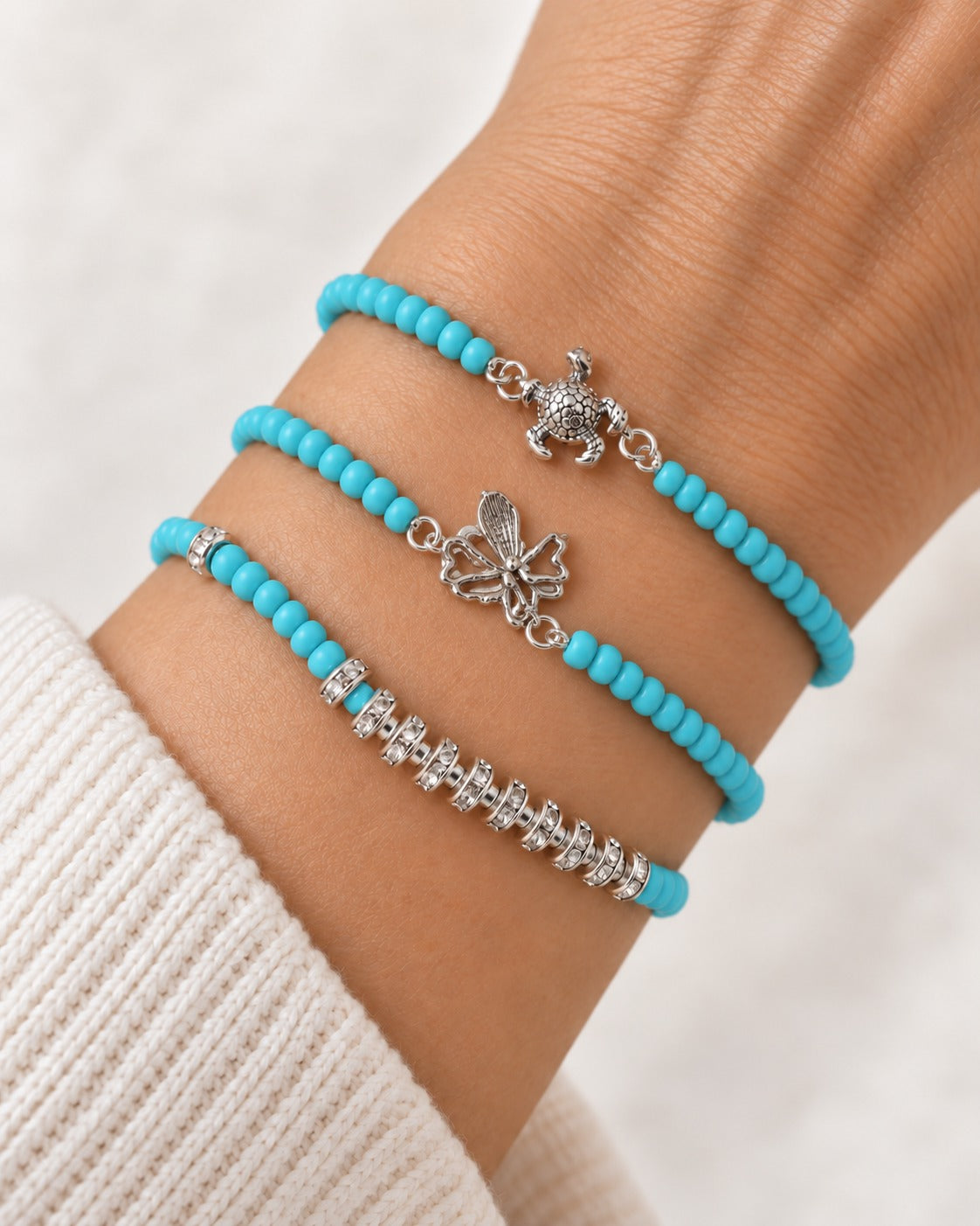 Ocean Charms Turquoise-Tone Bracelets worn together on the wrist, showing the turtle charm, the openwork winged charm and the sparkly spacer design
