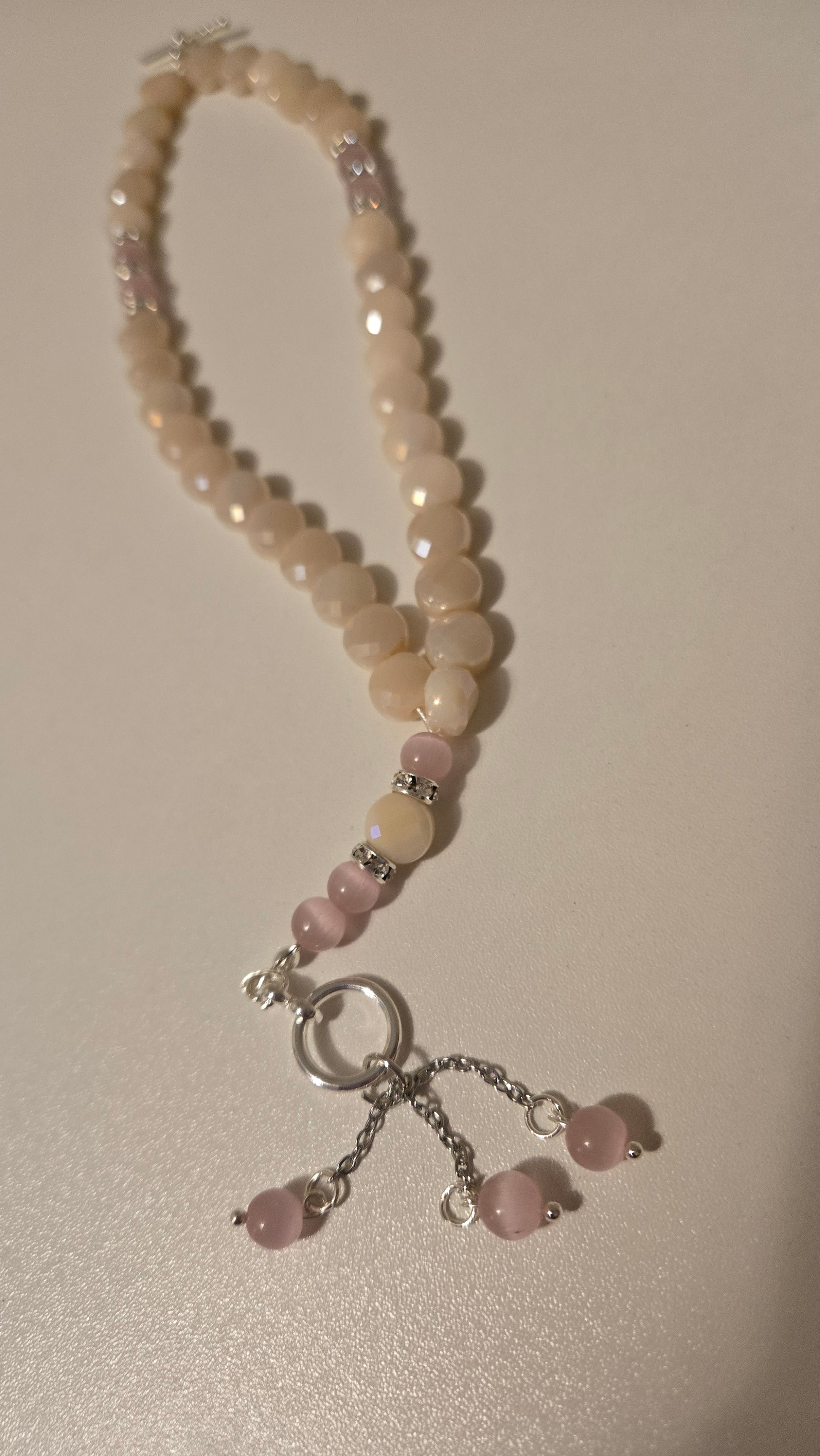 Artistic shot of the Rose Light Tasbih outdoors with flowers