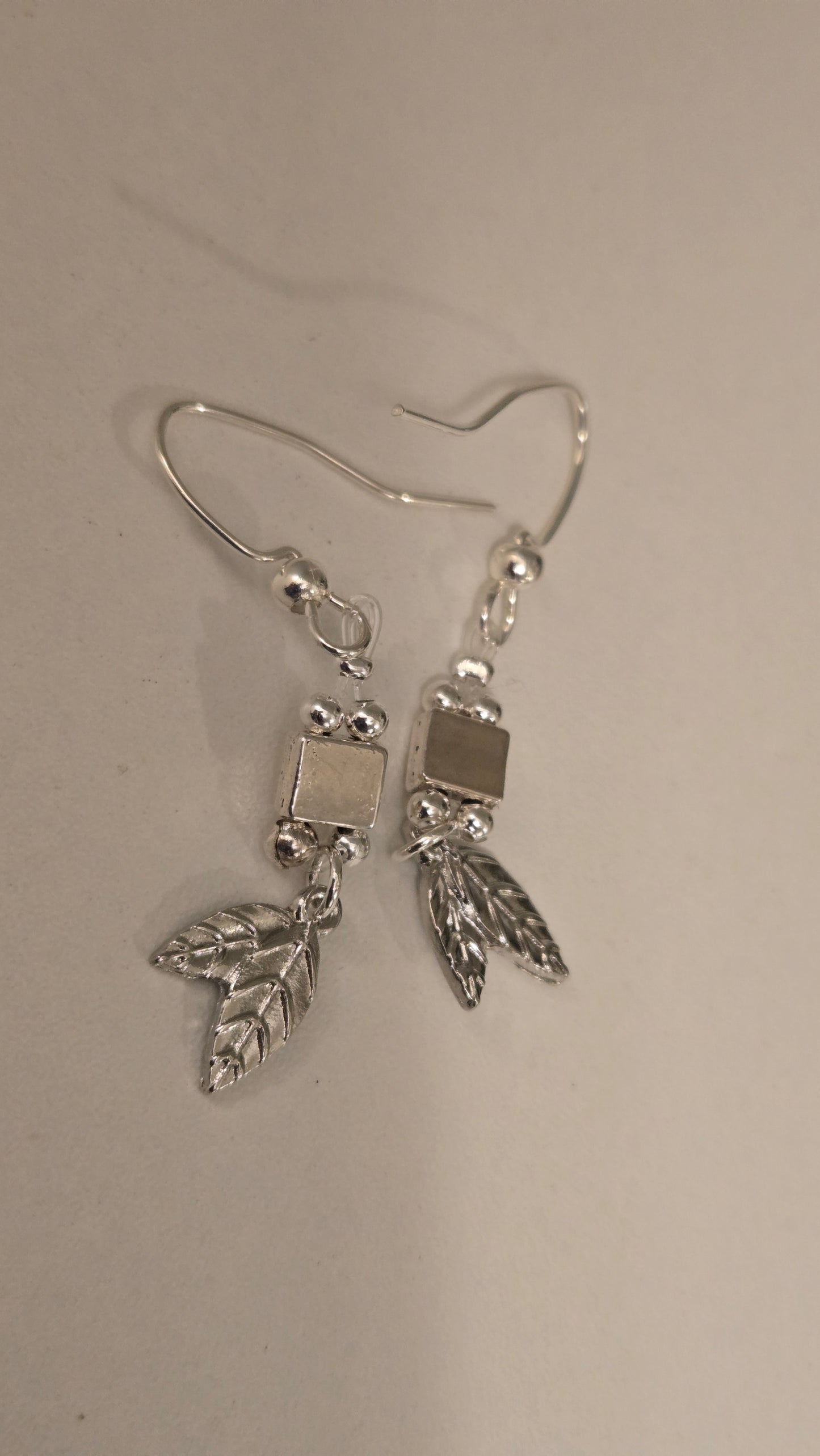 Detailed view of the smooth silver beads and geometric accent on the Leaf Drop Earrings