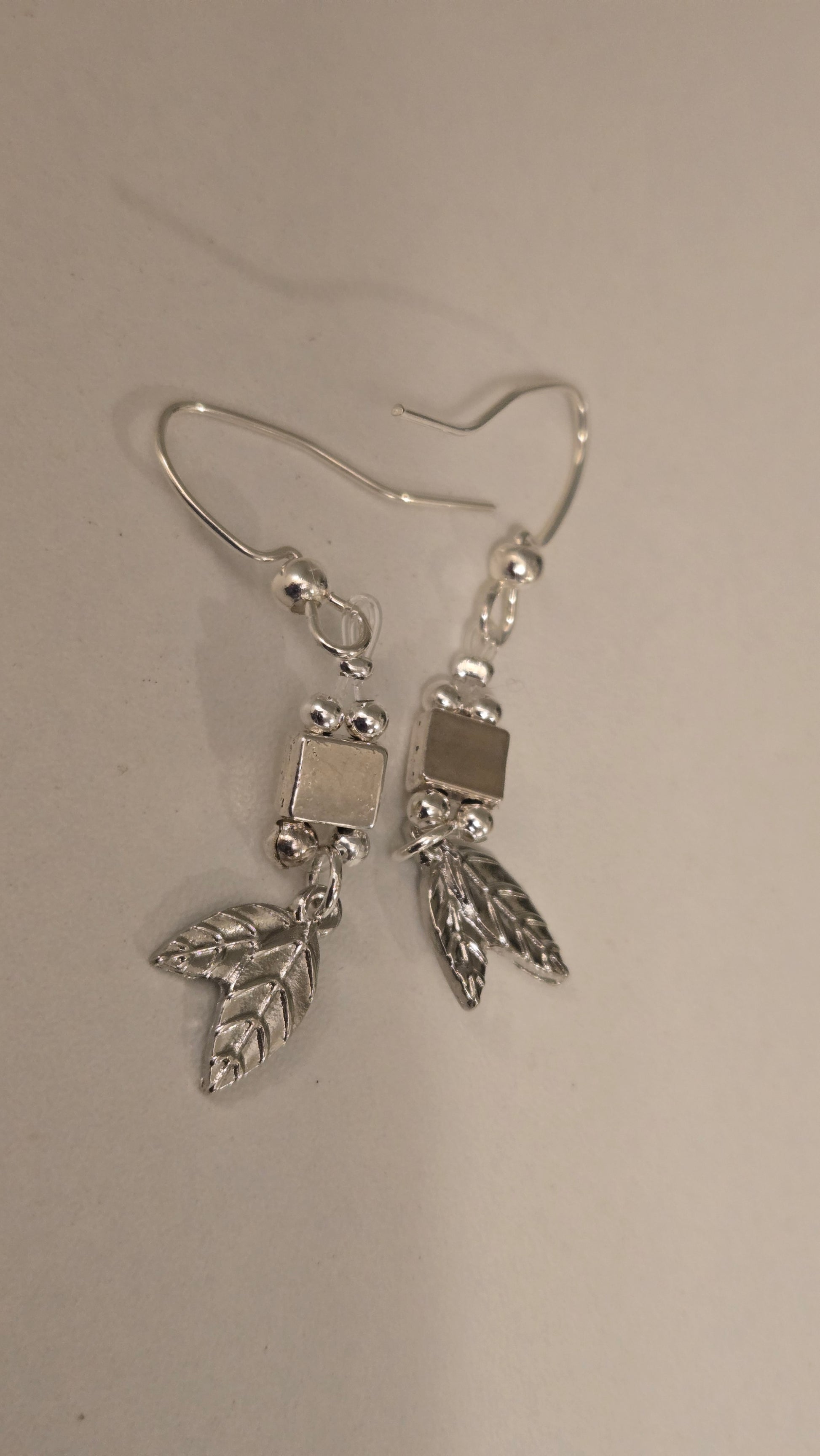 Detailed view of the smooth silver beads and geometric accent on the Leaf Drop Earrings