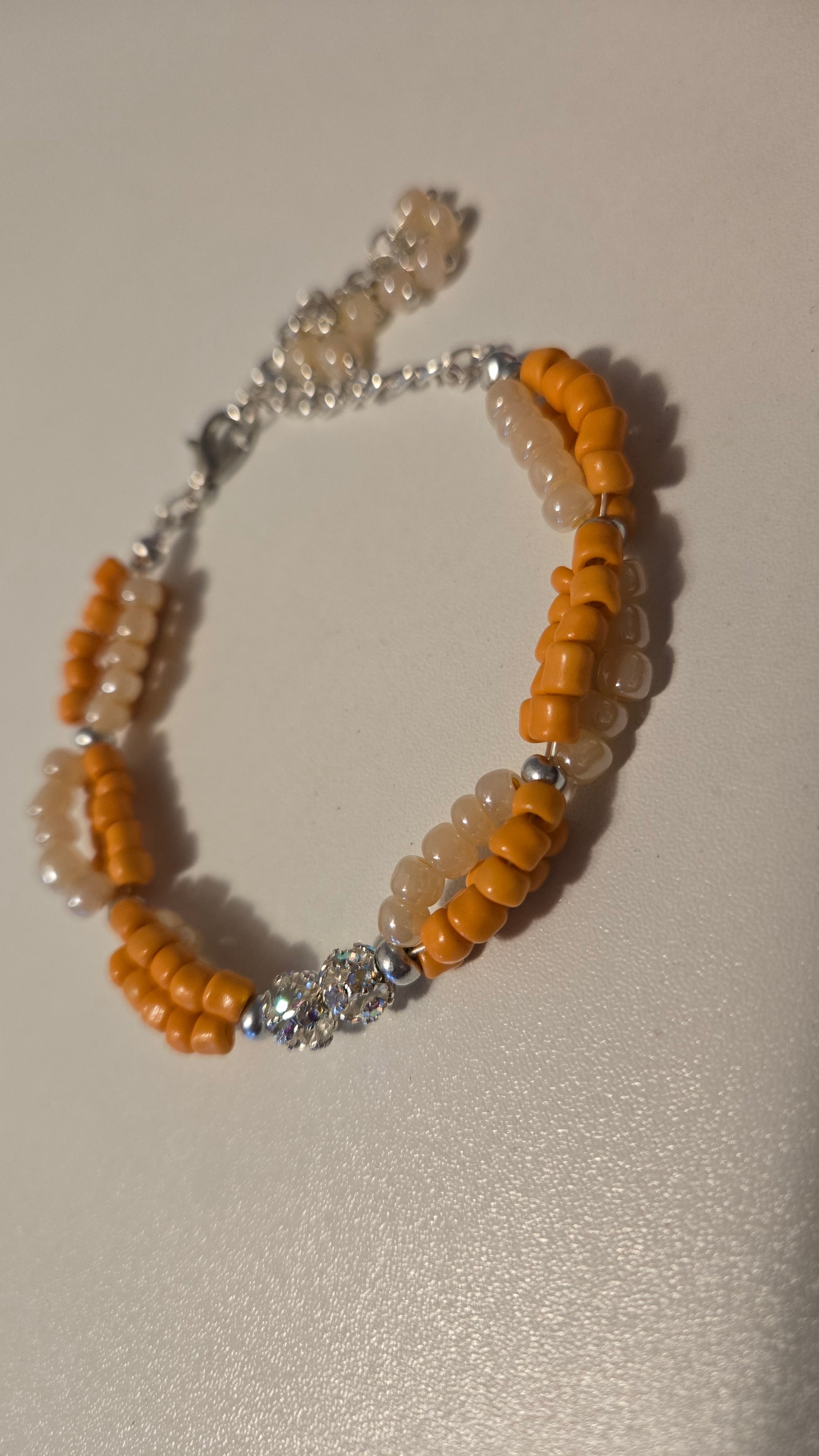 Coral Sun Handmade Beaded Bracelet on a model's wrist, showcasing its vibrant orange and ivory beads.