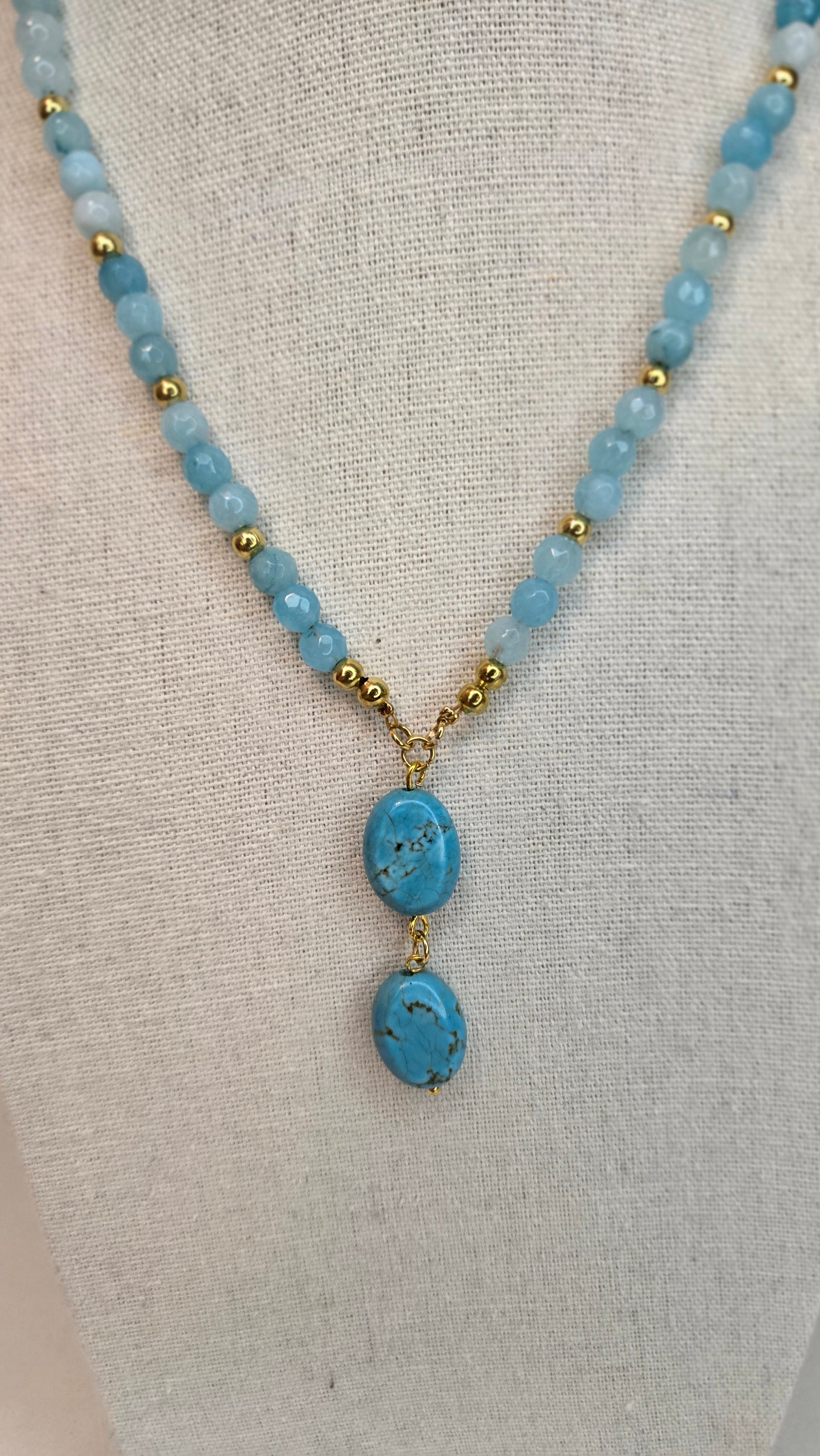 Close-up of drop-shaped natural blue quartz stones on an elegant gold accent necklace