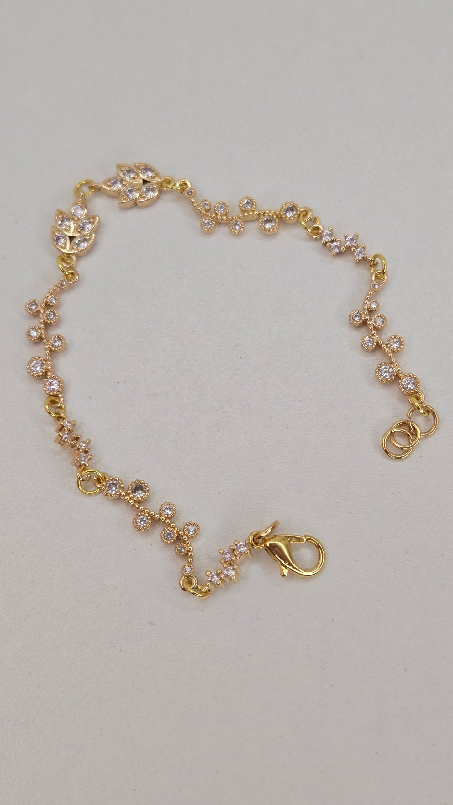Golden Flora Bracelet layered with other delicate gold jewelry, showing versatile styling options.