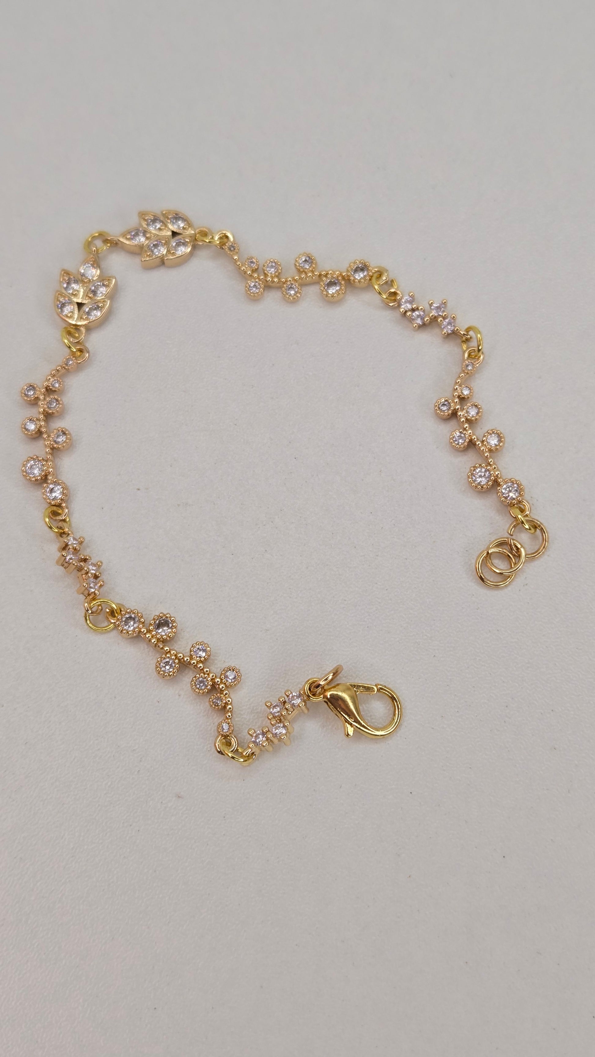 Overhead view of the Golden Flora Bracelet on a white surface, emphasizing its intricate floral pattern.