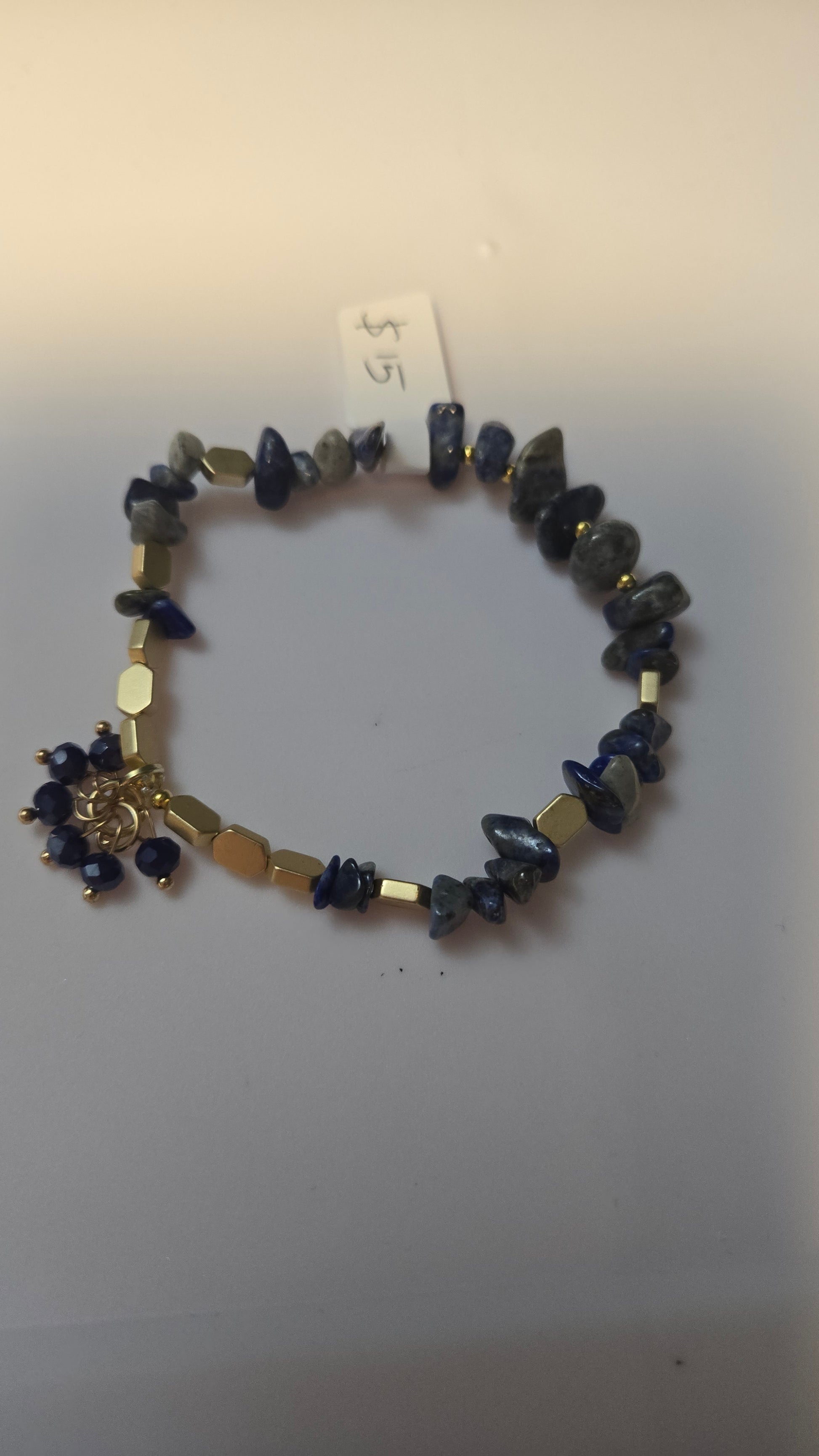 Close-up of the Blue Serenity Bracelet showcasing dark natural stone beads and intricate gold-tone metallic details.
