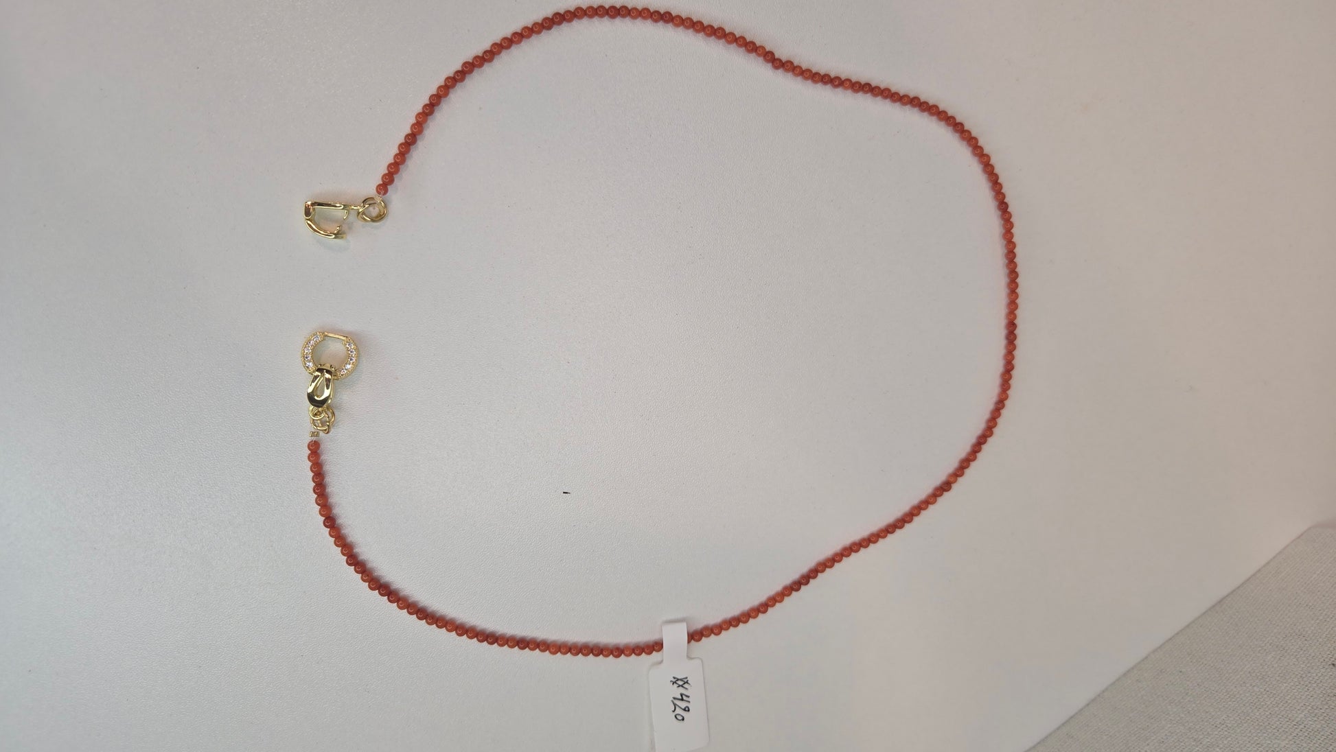 Top-down view of the delicate coral beads and central gold charm of the Coral Whisper Necklace