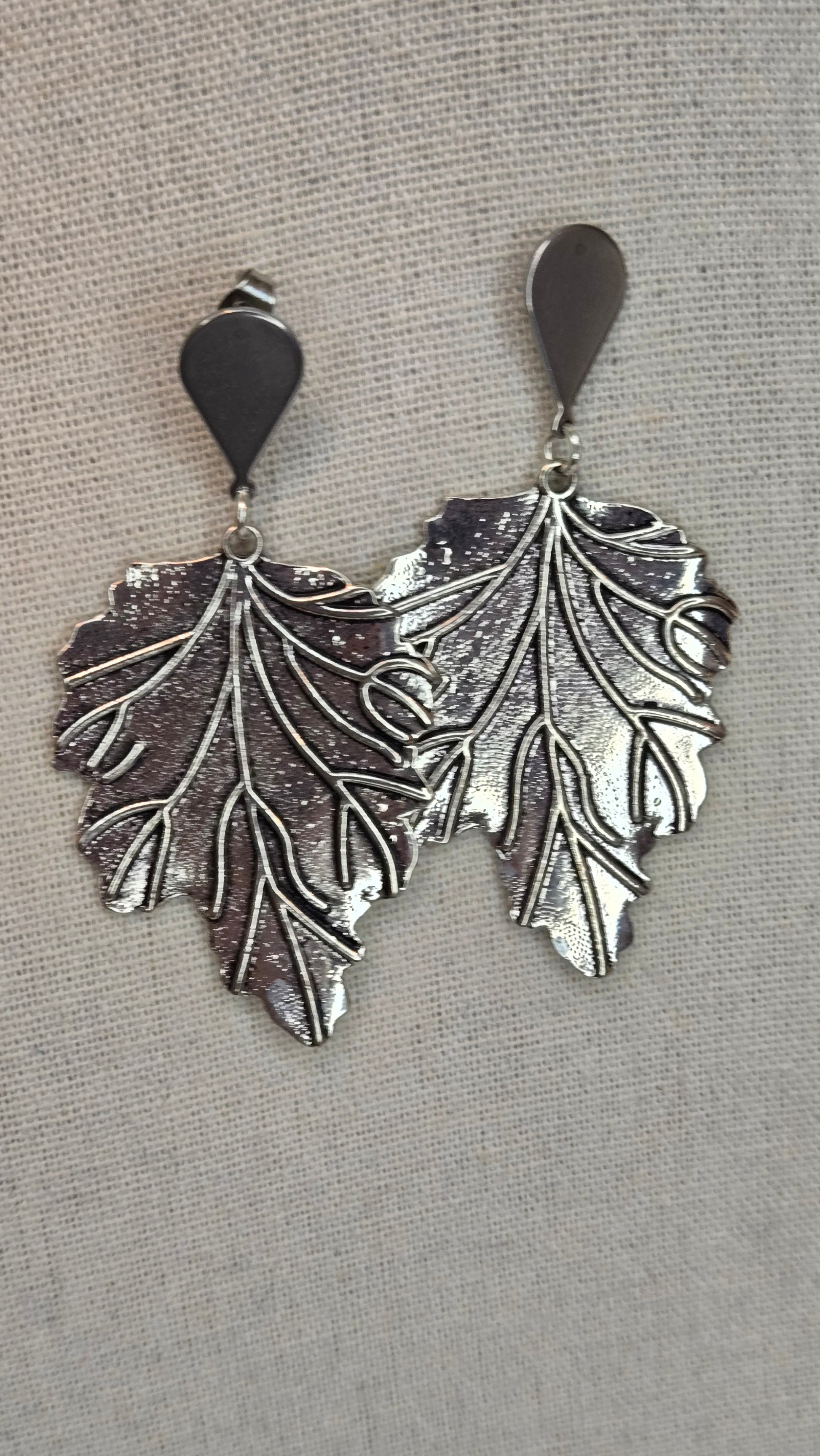 Close-up of silver leaf earrings with intricate details