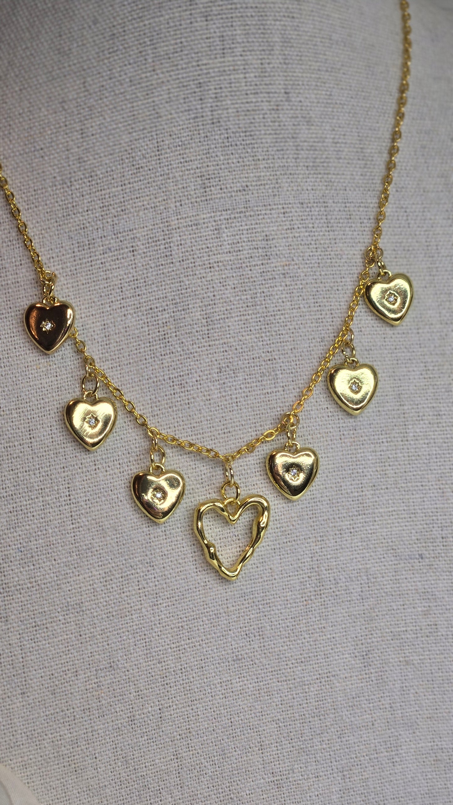 Golden Heart Charm Necklace hanging elegantly on a display stand