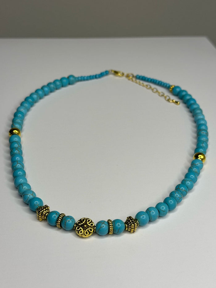 Elegant Turquoise Necklace with turquoise-colored beads, gold-tone spacers and charms