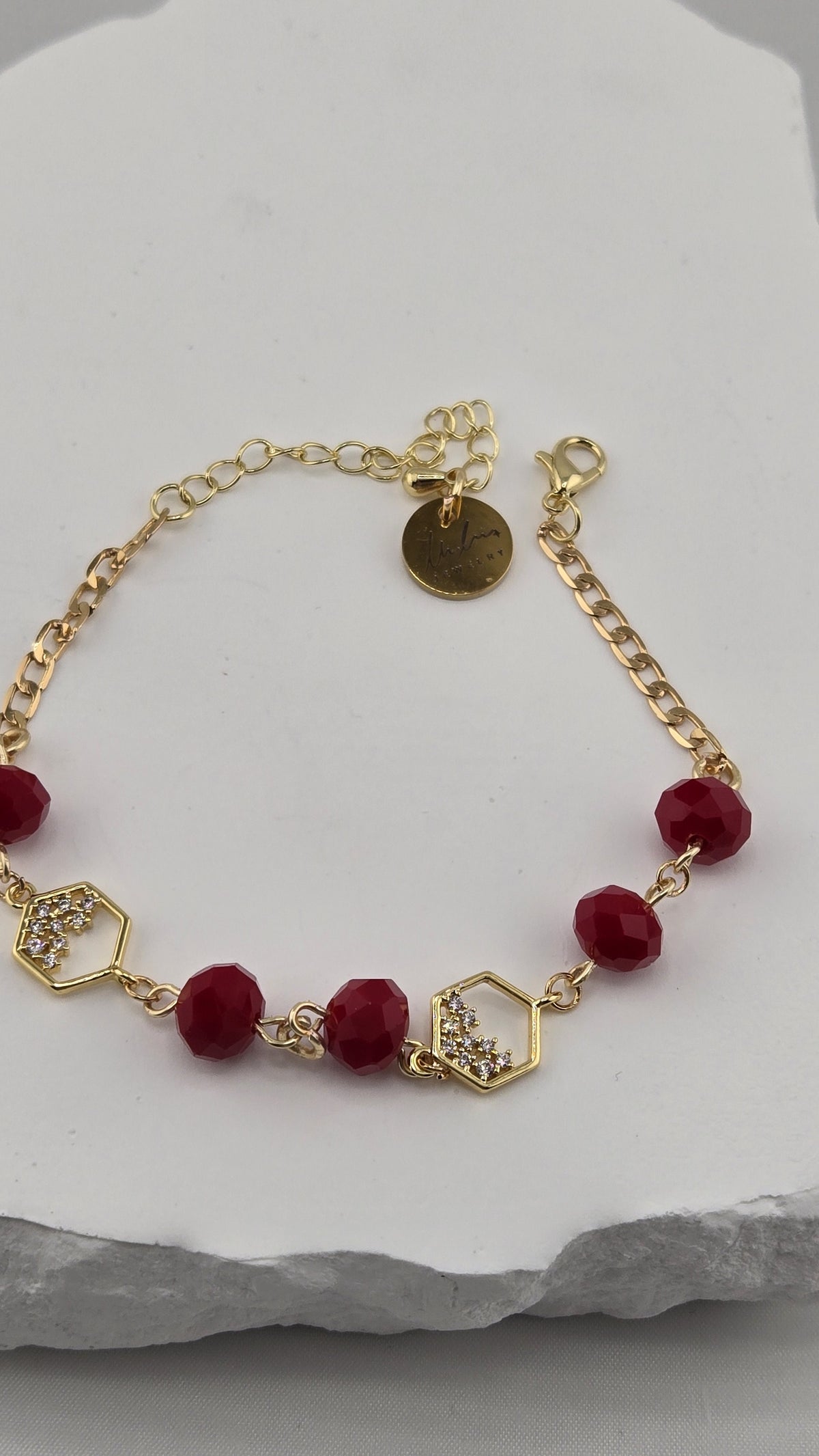 Close-up of hexagon links set with clear stones, red beads and LuluTouch tag
