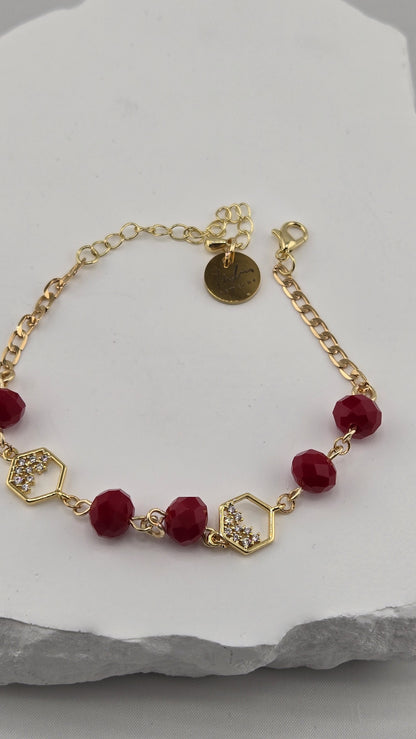 Close-up of hexagon links set with clear stones, red beads and LuluTouch tag