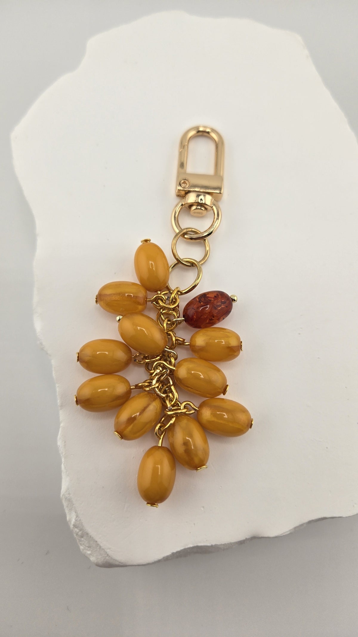 Butterscotch Bag Charm laid flat on a white stone, showing the swivel clip and bead cluster