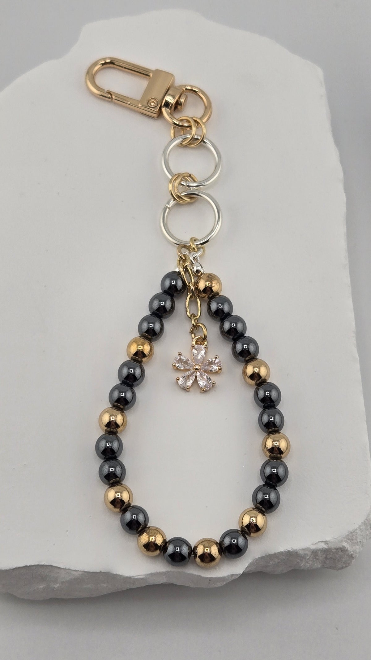 Gold-tone swivel clip and clear-stone flower charm on the Charcoal Gardenia Bag Charm