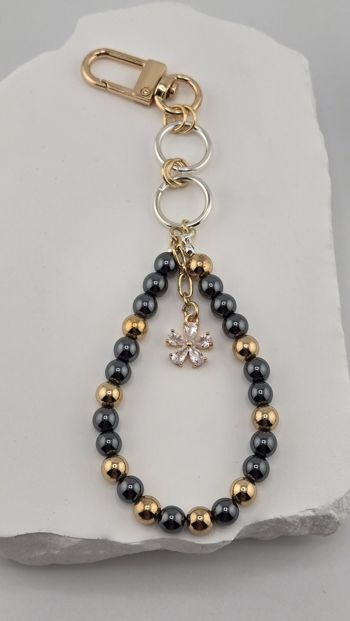 Charcoal Gardenia Bag Charm with gold-tone and dark gray hematite beads and a flower charm