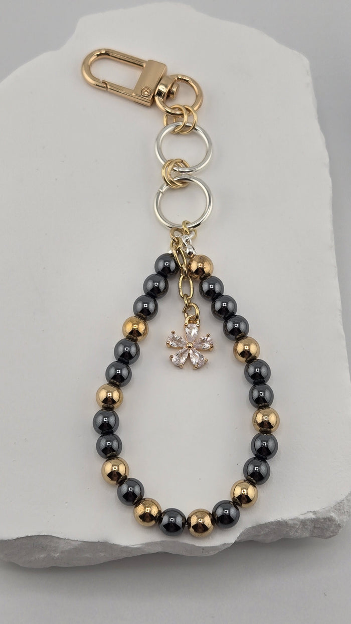 Charcoal Gardenia Bag Charm with gold-tone and dark gray hematite beads and a flower charm