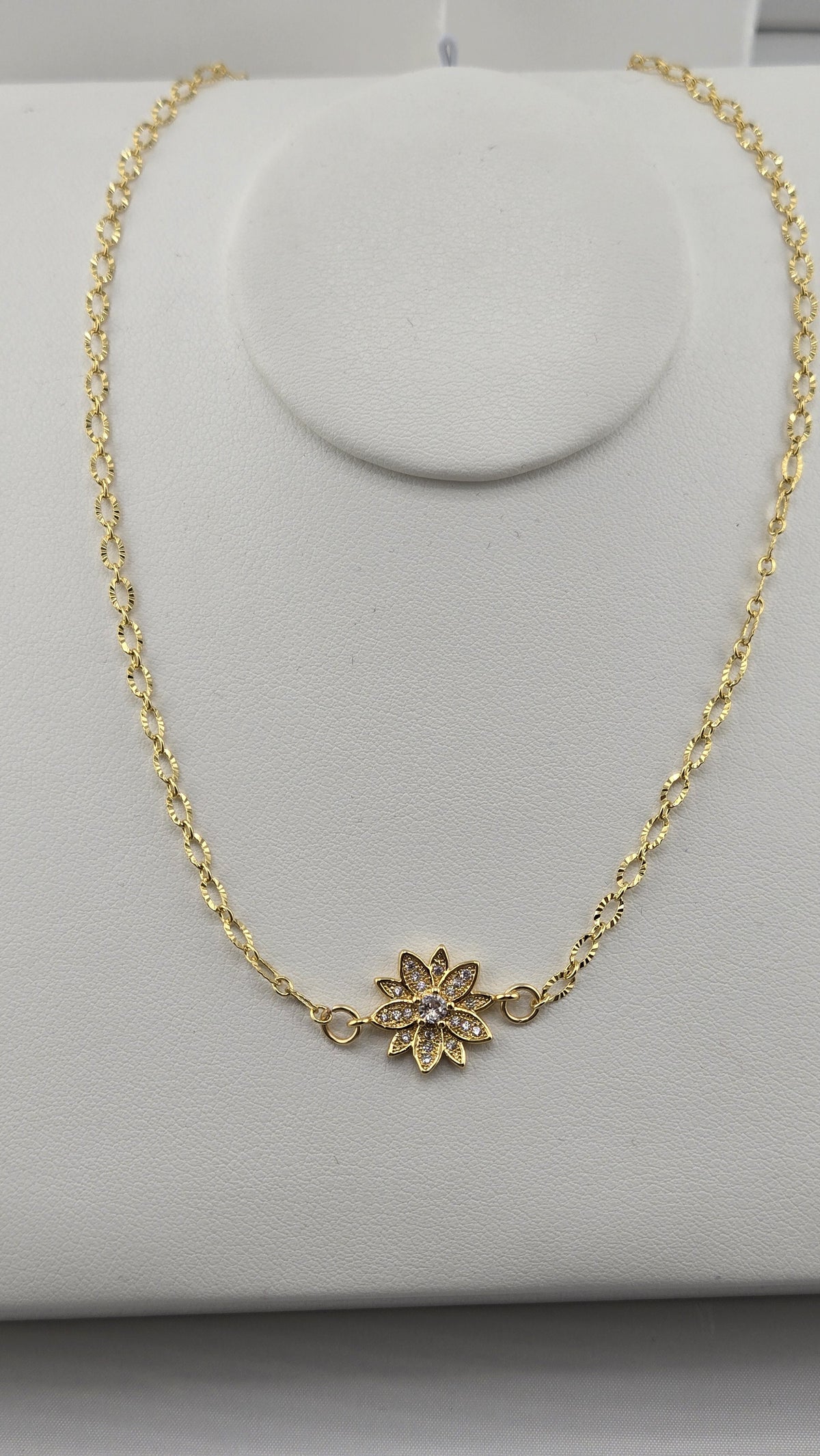 Gold flower set with small clear stones on a textured gold-filled chain