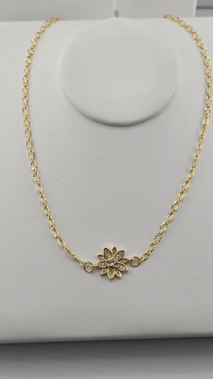 Gold flower set with small clear stones on a textured gold-filled chain