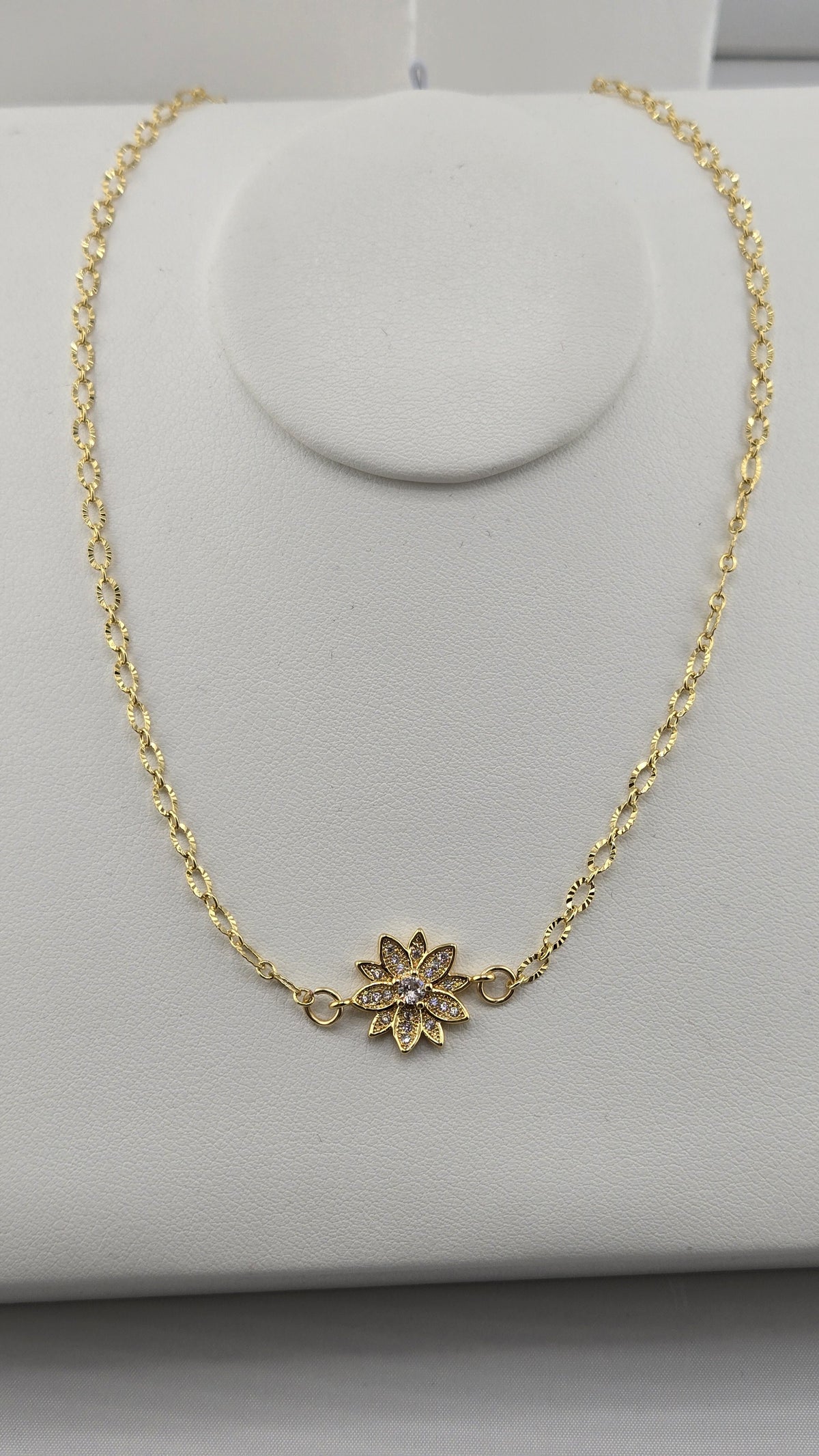Dahlia Gold-Filled Necklace with a sparkling gold flower centerpiece on a necklace stand
