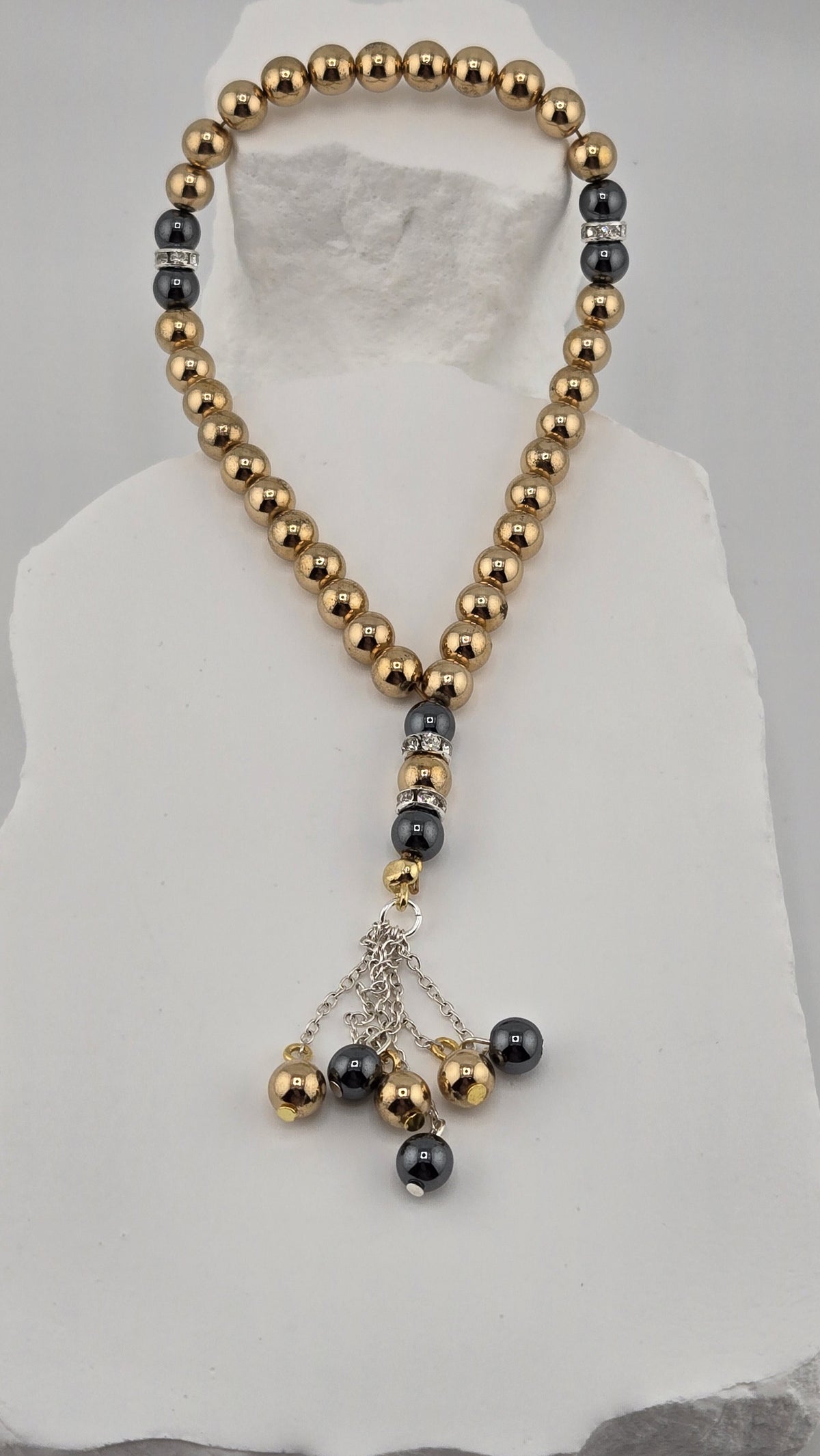 Gilded Dusk Tasbih laid on a white stone surface