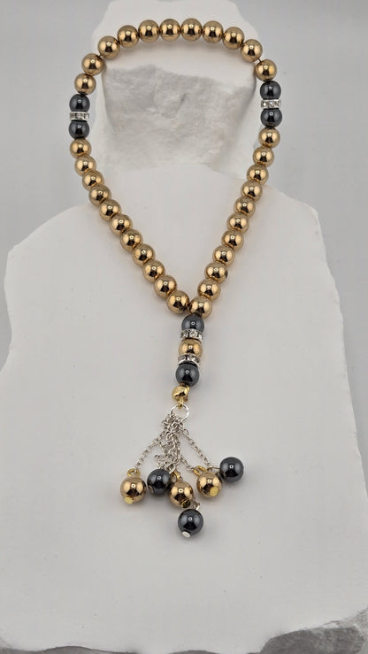 Gilded Dusk Tasbih laid on a white stone surface