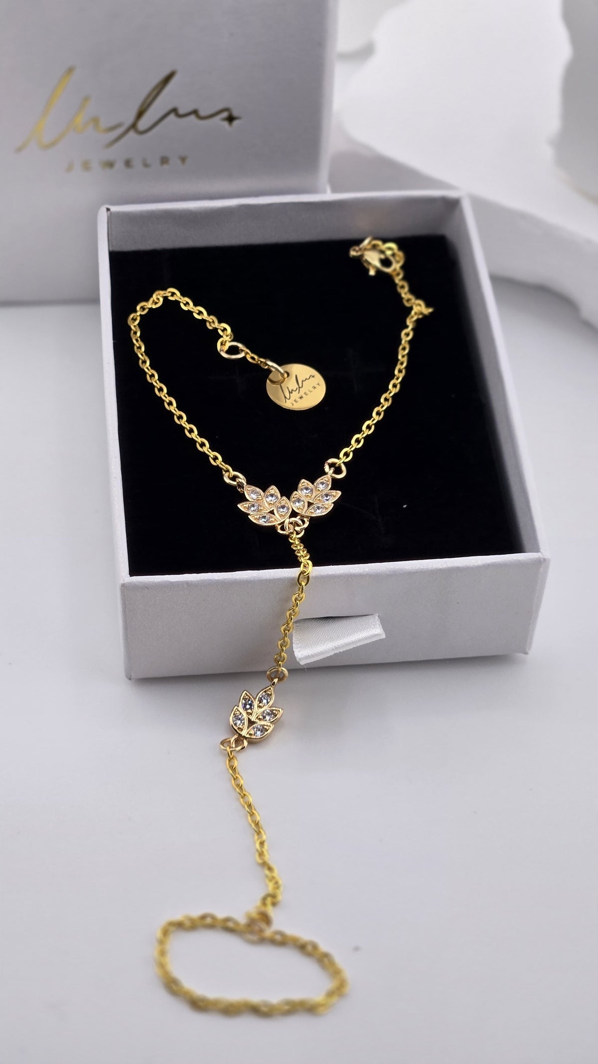 Golden Laurel Hand Chain in a LuluTouch gift box, close view of the gold-tone leaf charms with clear stones