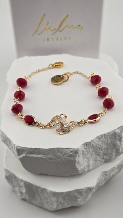 Hibiscus Pinwheel Bracelet with deep red beads and a gold flower centerpiece