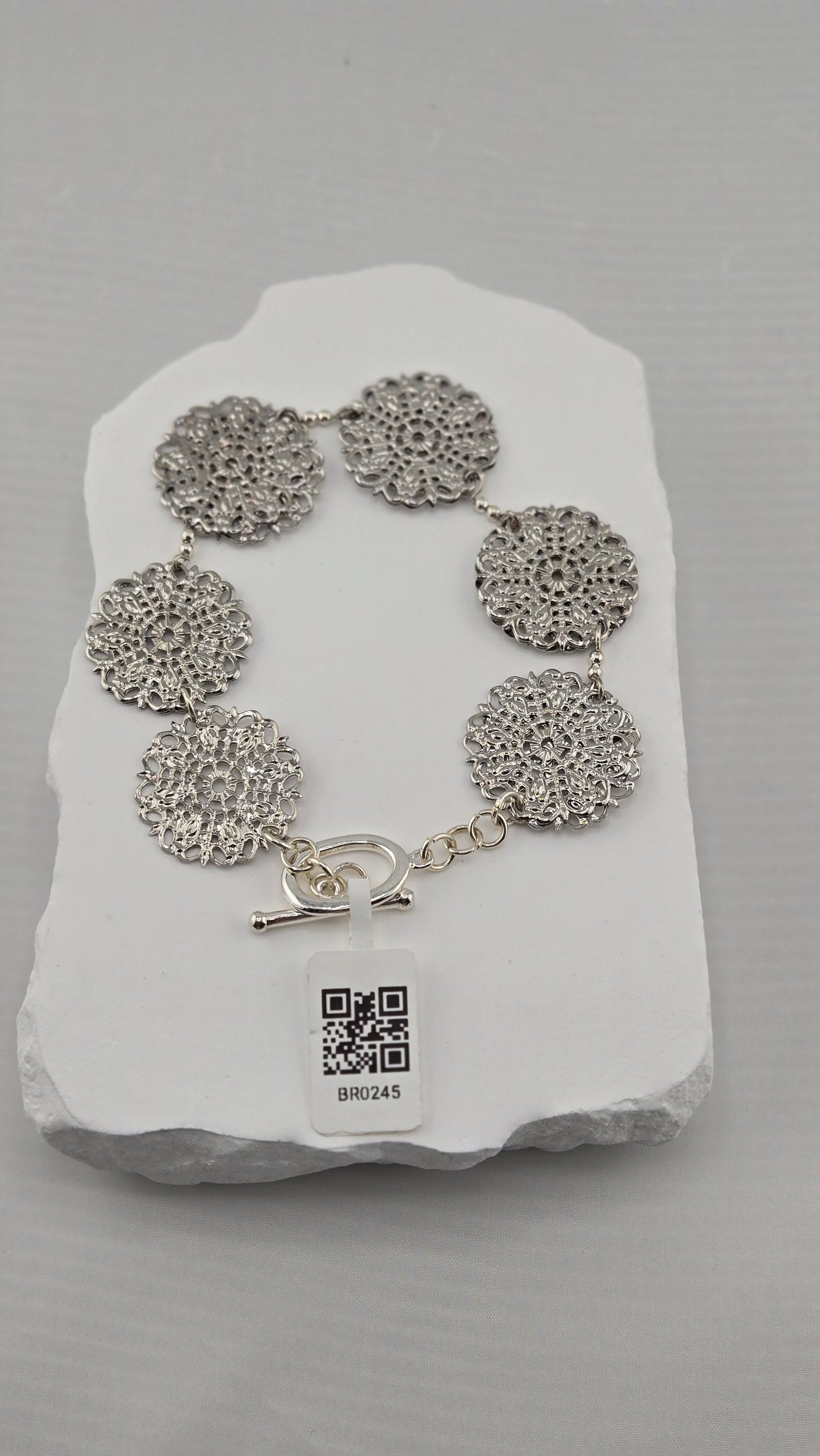Six silver-tone openwork rosettes with toggle clasp