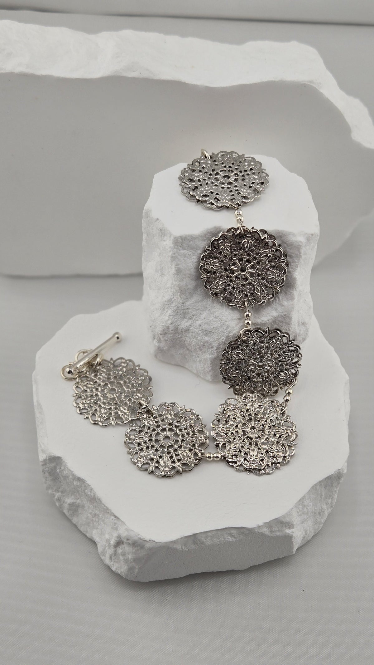 Rosette Openwork Bracelet draped over white stones