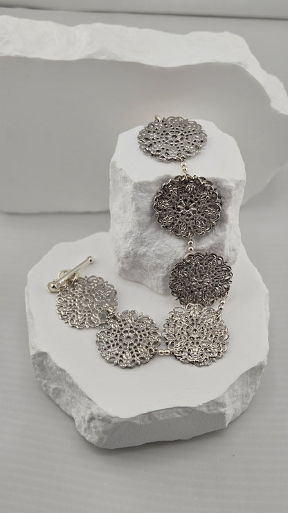 Rosette Openwork Bracelet draped over white stones