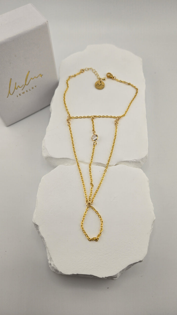 Solitaire Hand Chain with three gold chains and one clear stone beside the LuluTouch box